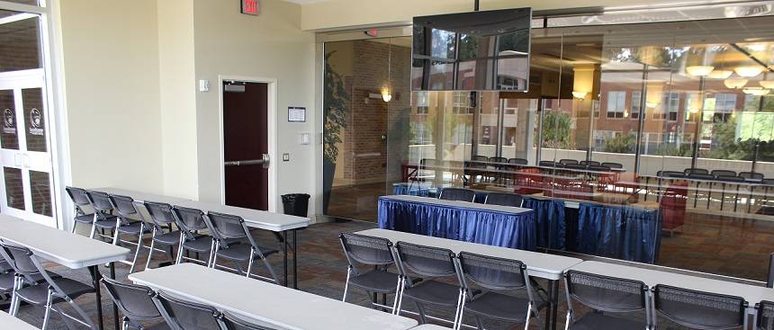 tables and chairs set up for meeting in glass room in student center