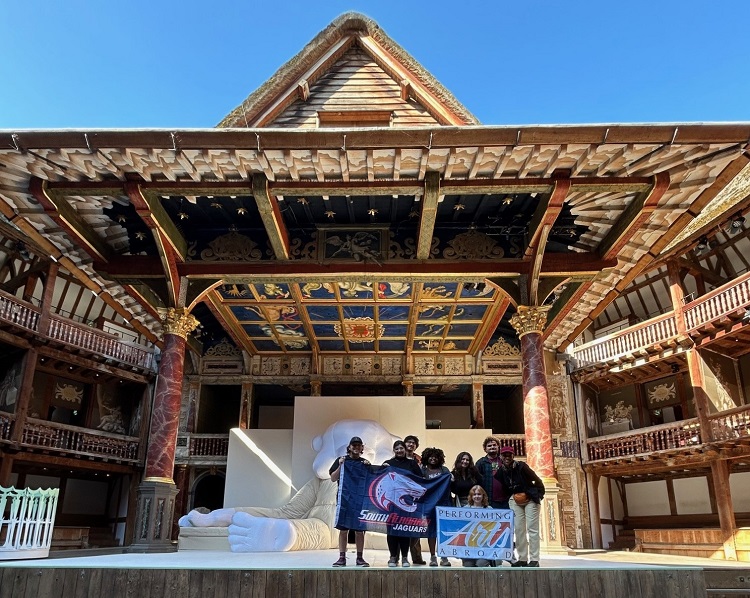 Ari and group in Globe Theater A group of students stand on stage in the Globe Theater in London.