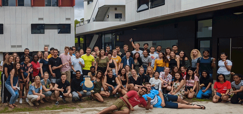 A large group of students take a picture in from of the international dorms.