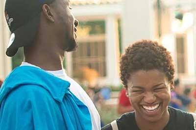 A male and female student laughing outside at a Jaguar Productions event.