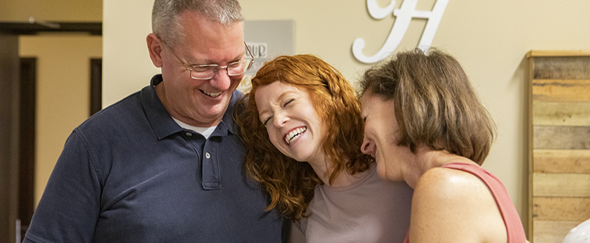 Parents with daughter in dorm room hugging.