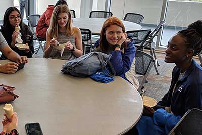 Students talking and smiling around a round table.