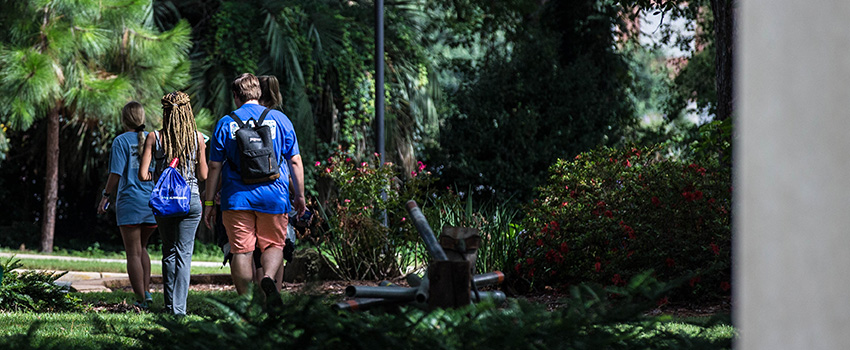 Two students walking on campus with flowers in background.