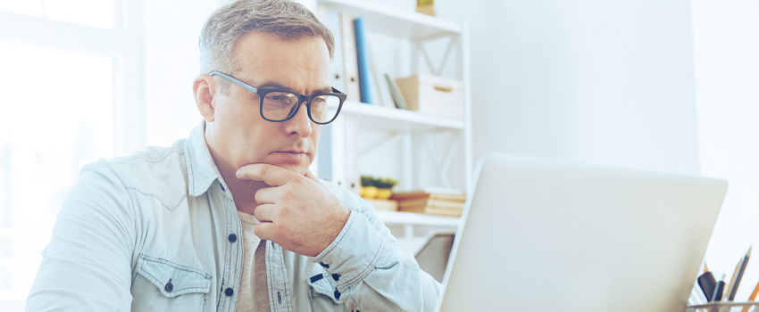 Man with glasses on working on laptop