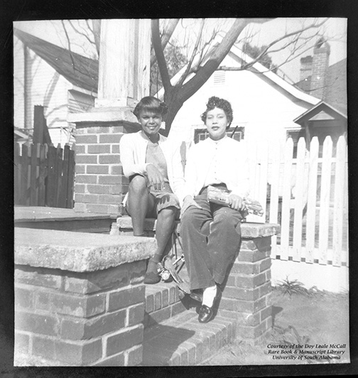 Two young women on porch steps holding roller skates.