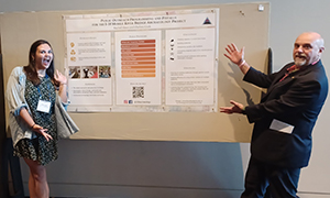 Professor and student pointing to research poster.