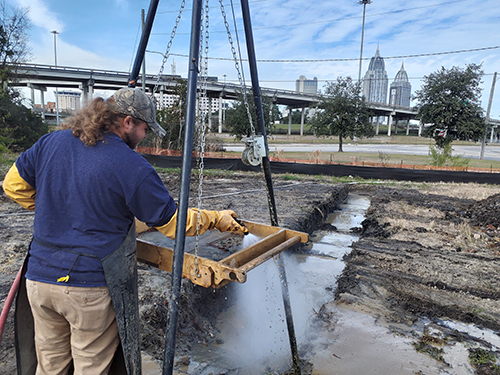 A field crew member screening soil recovered from a site on I-10 Mobile River Bridge Archaeological Project.