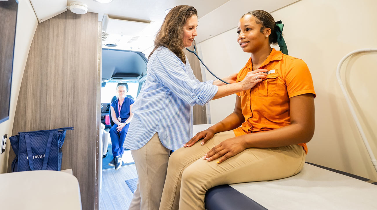 Medical worker listening to heart of student.