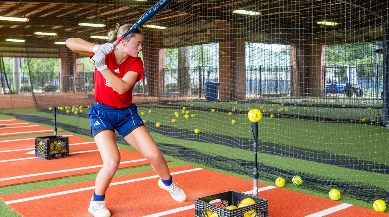 Megan practicing hitting at a batting cage.