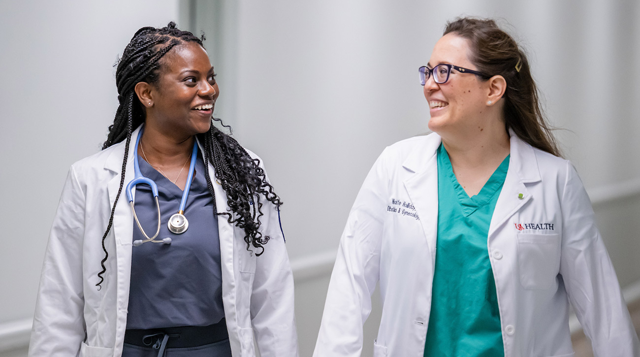 Nia speaking with a medical colleague in the hall.